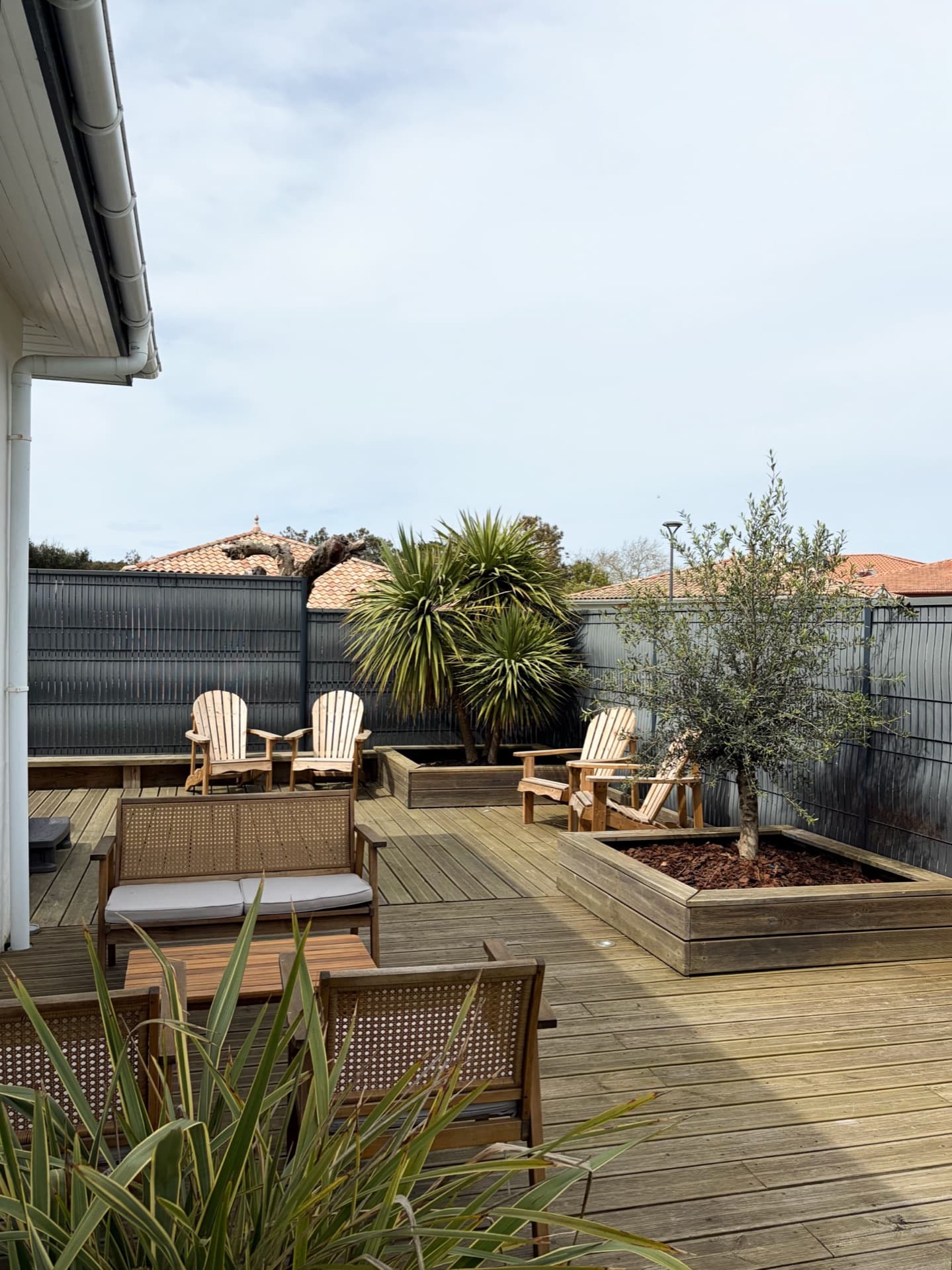 Terrasse en bois avec salon canné, fauteuils Adirondack et jardin clos paysager