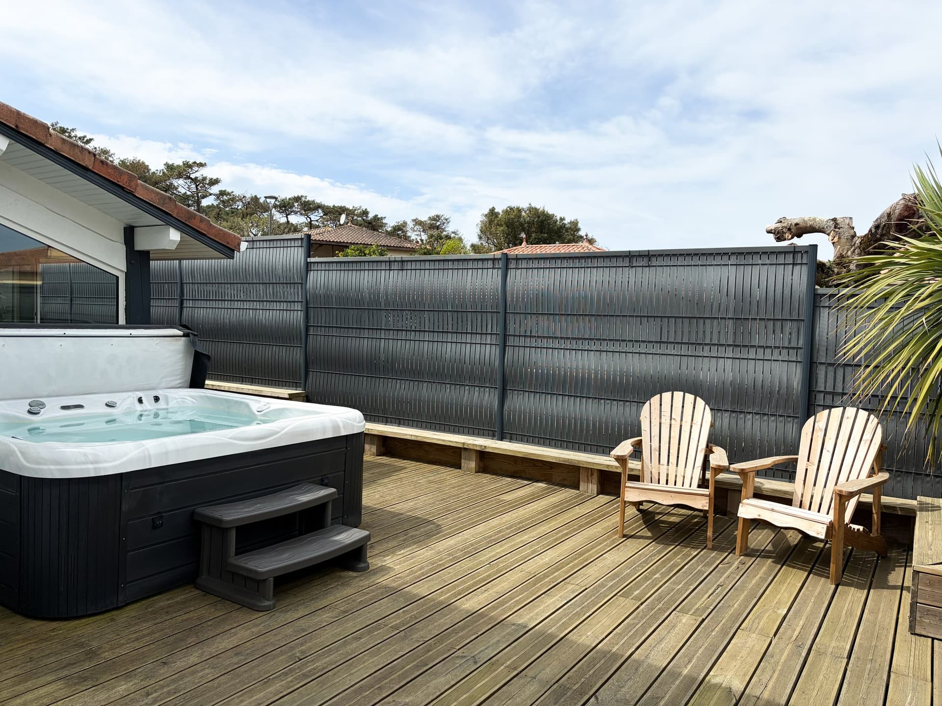 Jacuzzi privatif chauffé et terrasse en bois de la maison à Moliets-Plage, fauteuils Adirondack et jardin