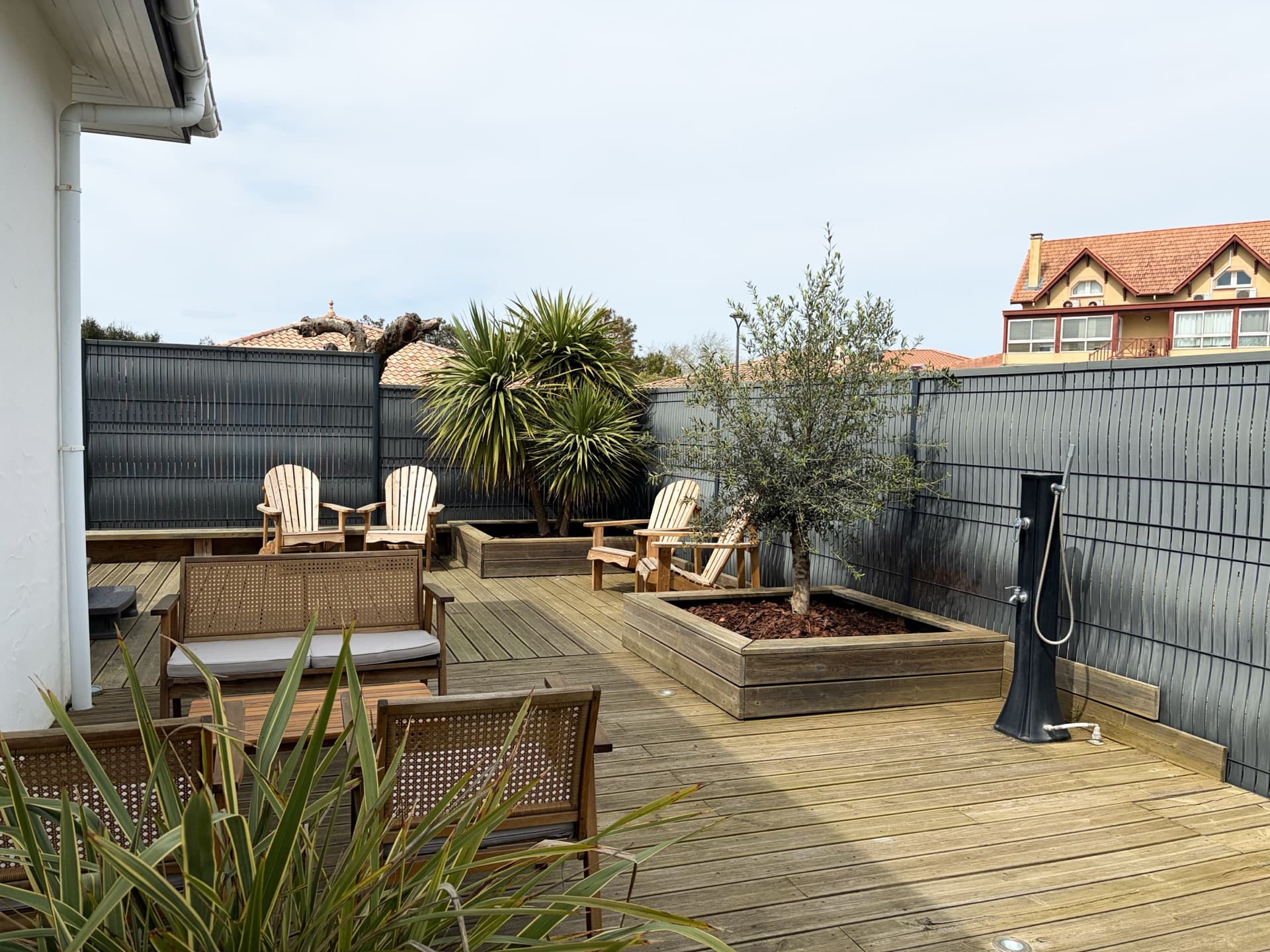 Terrasse en bois avec fauteuils Adirondack, olivier en pot et douche extérieure